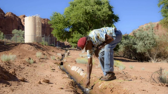A person collecting water from a shallow desert stream.